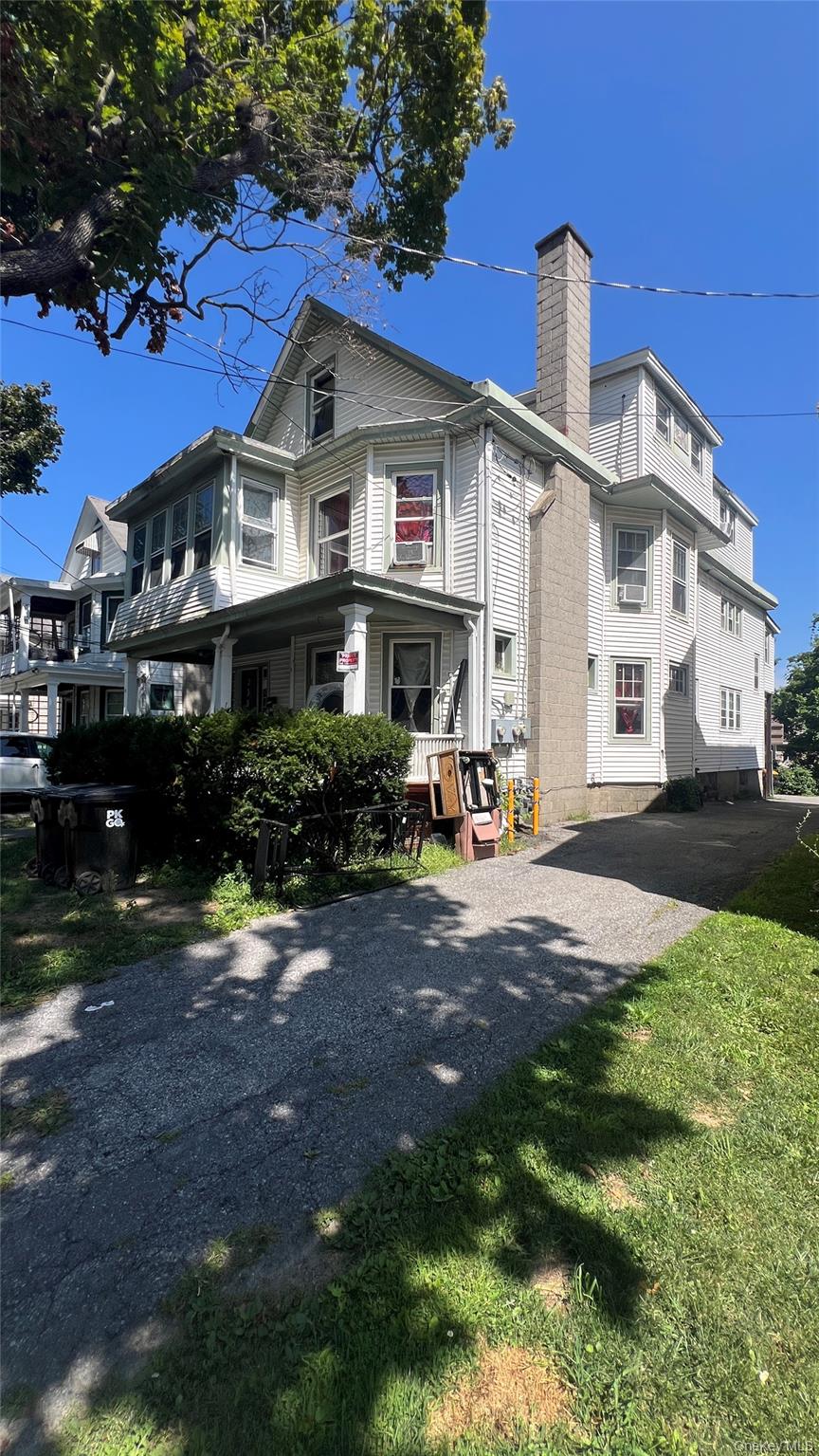 Back of house featuring a chimney and a lawn