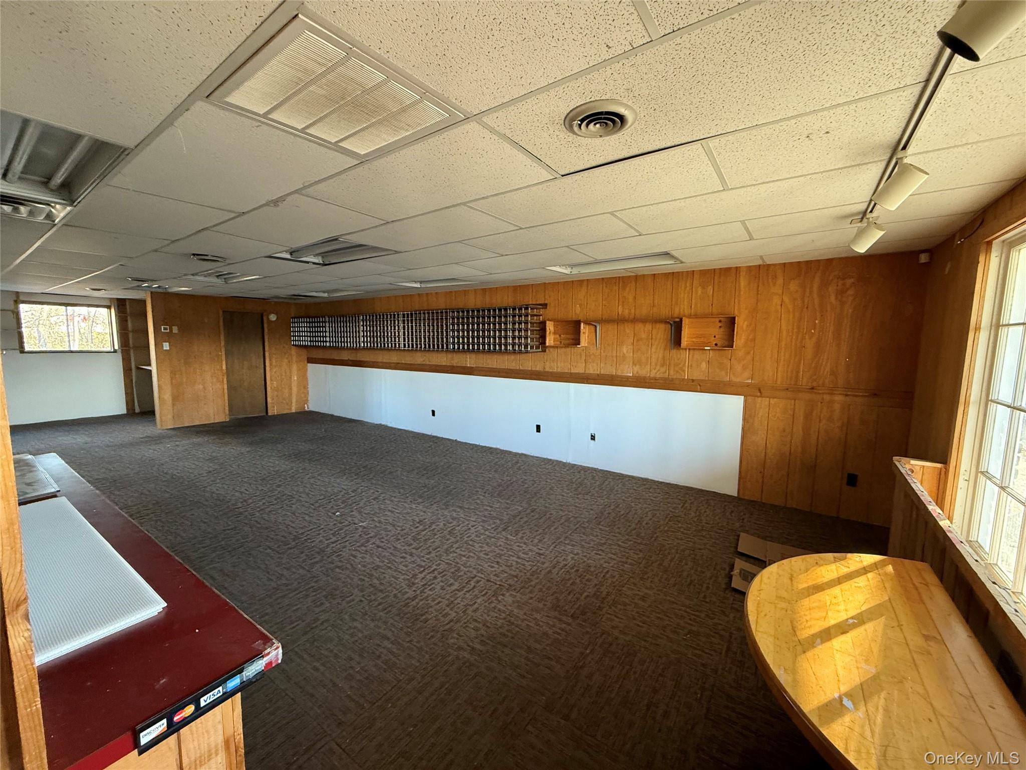 Carpeted empty room with wood walls and a paneled ceiling