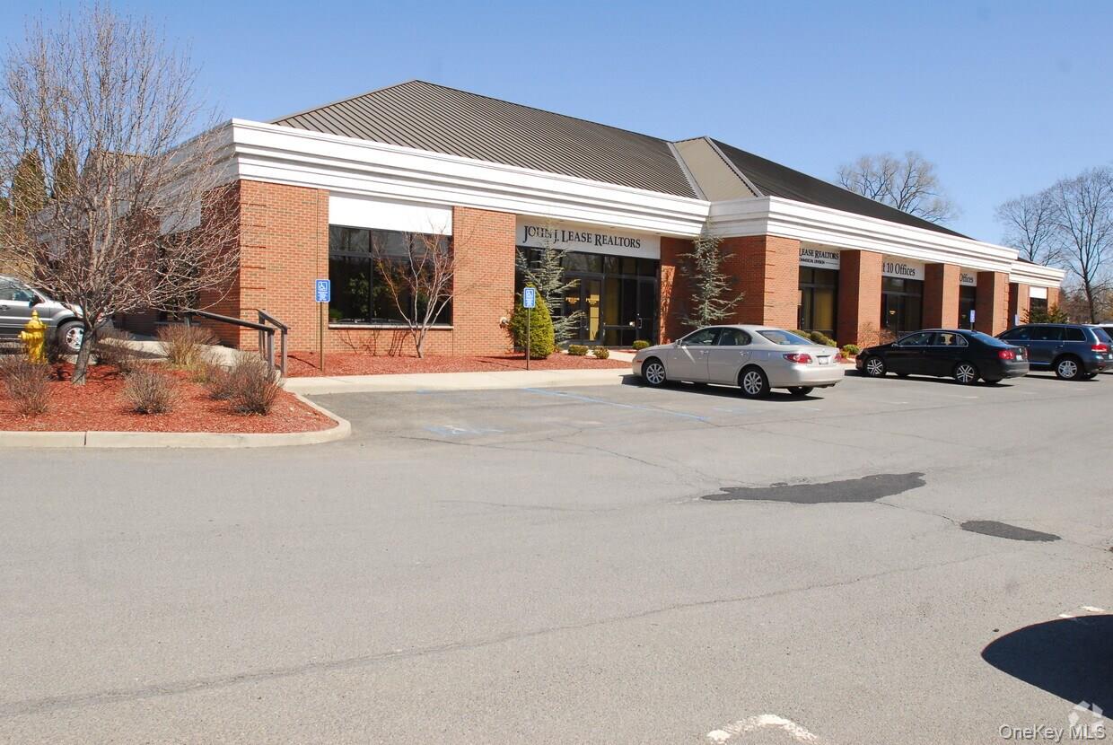 Commercial building featuring a brick facade, white trim, and a dark metal roof