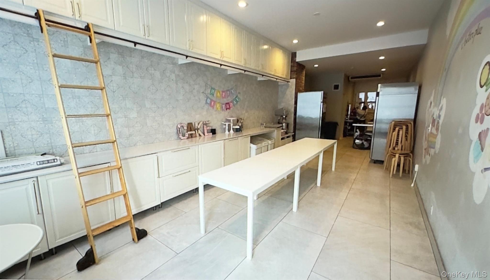 Kitchen with white cabinets freestanding refrigerator, recessed lighting, light stone countertops, and backsplash