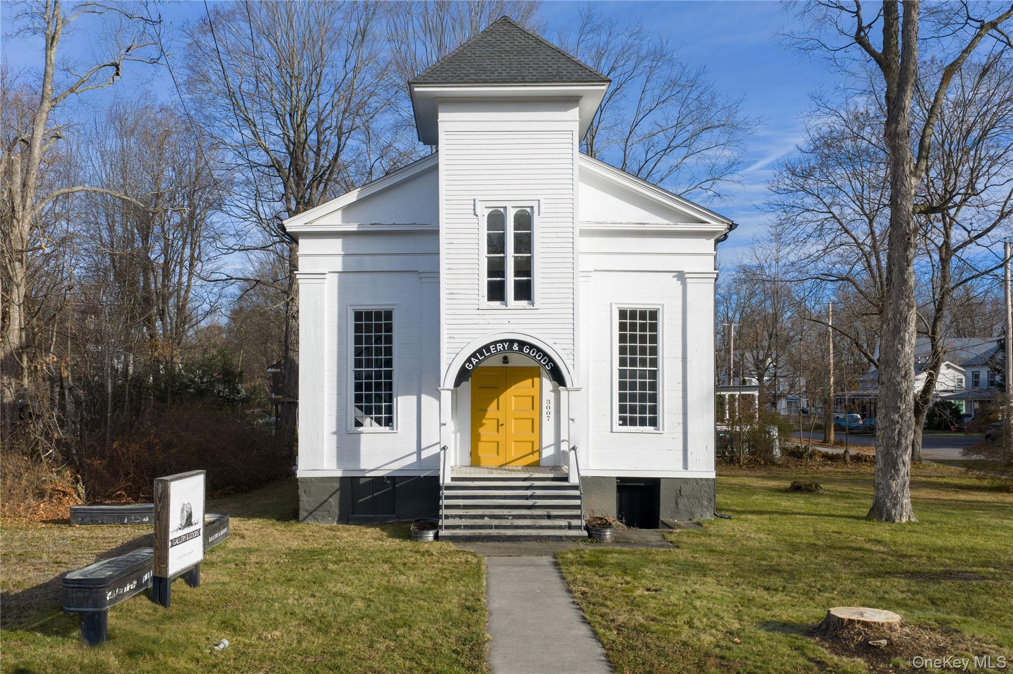 Greek revival inspired property featuring a front lawn and a shingled roof