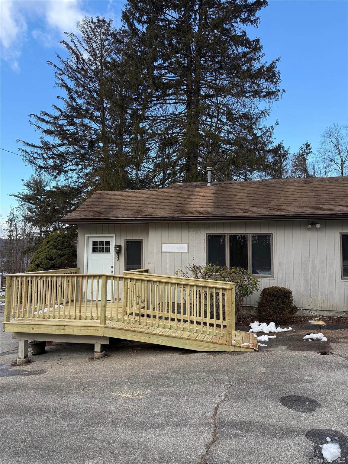 View of front of house with a shingled roof and a deck