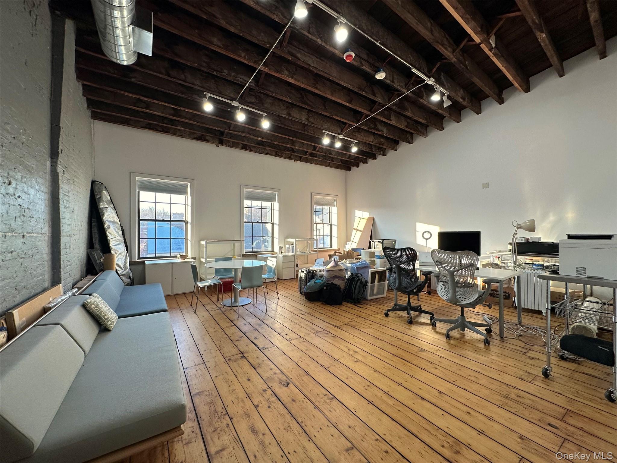 Miscellaneous room featuring track lighting, a desk, hardwood / wood-style floors, and a high ceiling