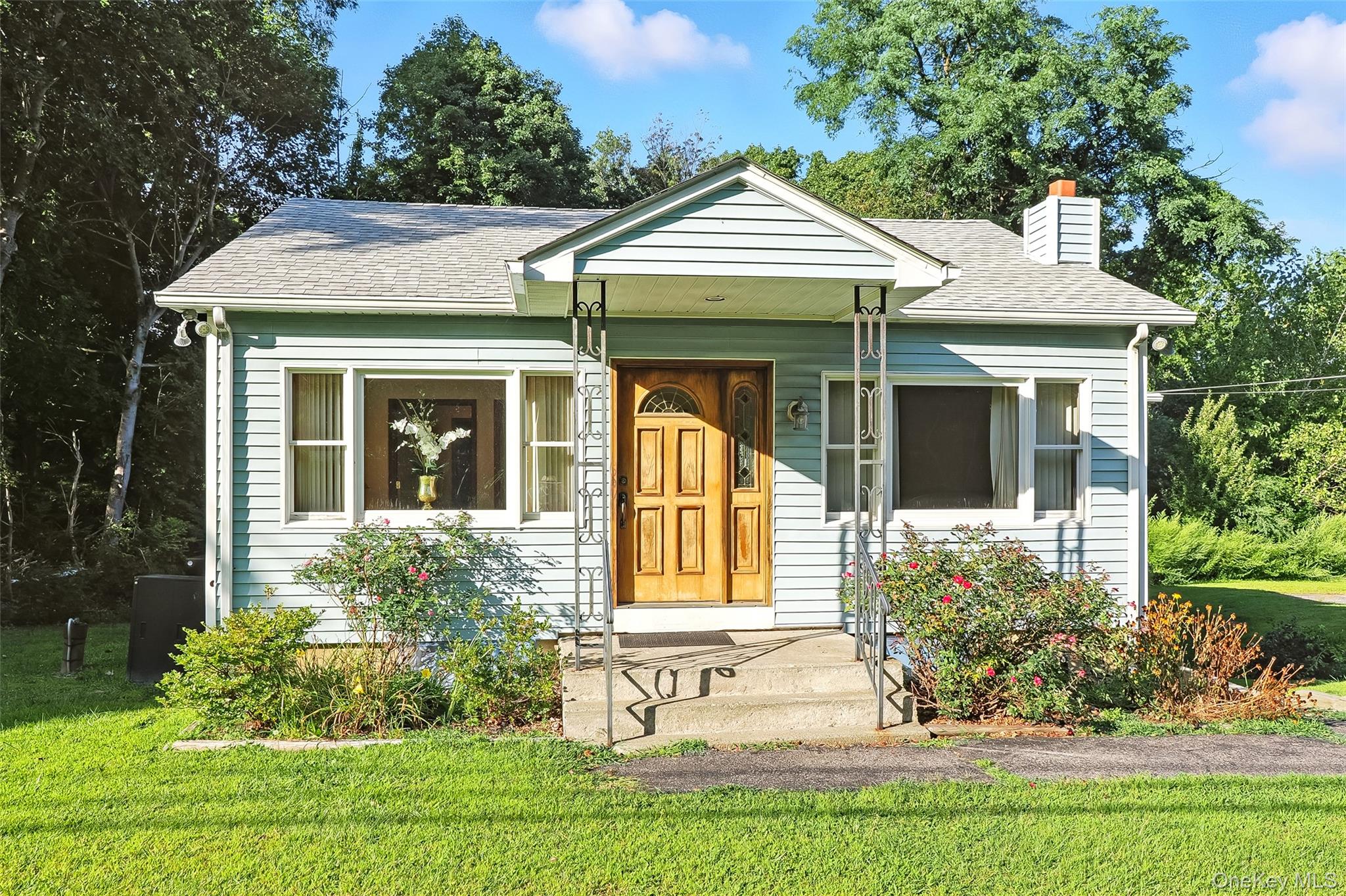 Bungalow-style house with a front lawn, roof with shingles, and a chimney