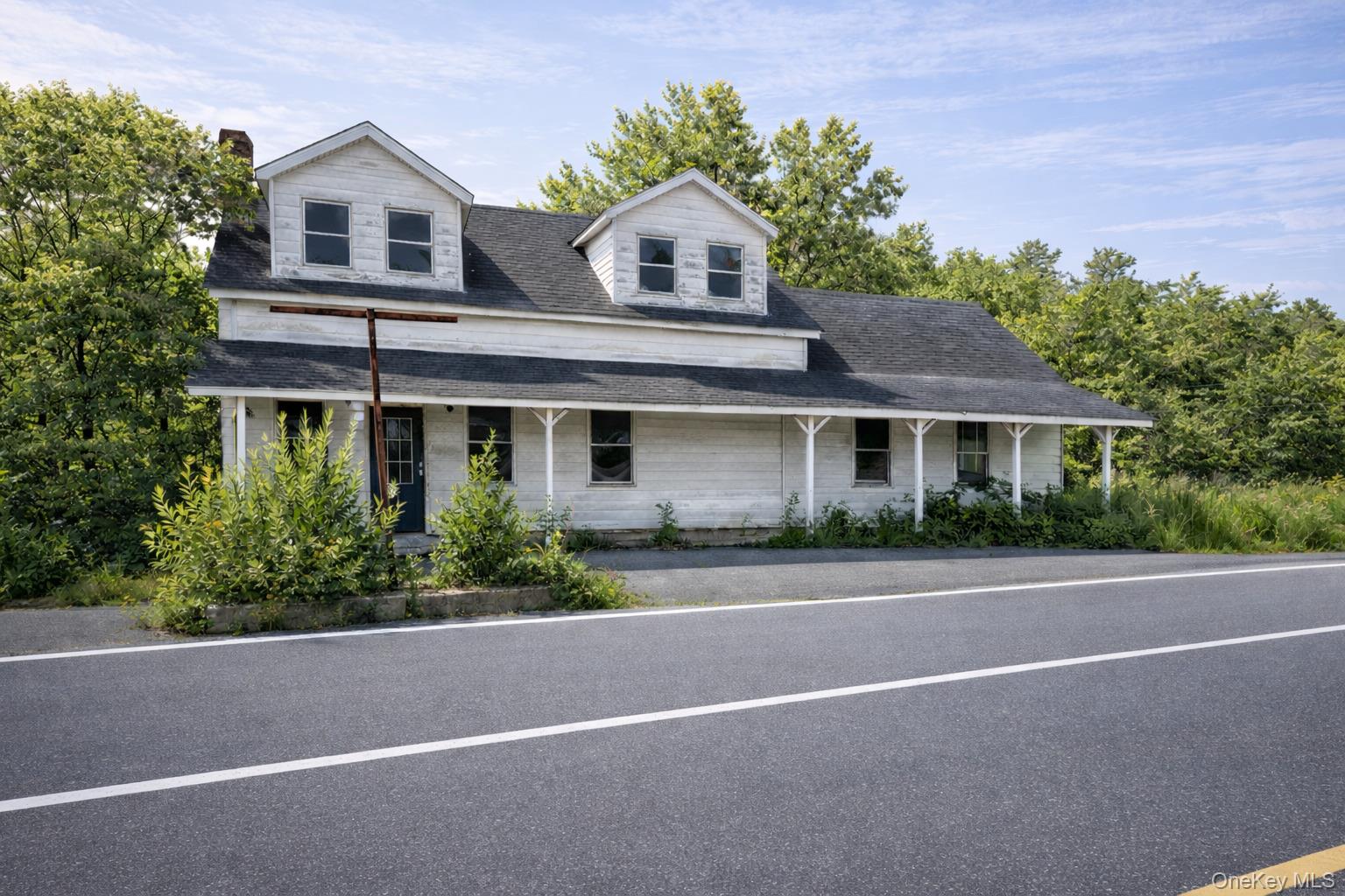 View of front of house with a porch, a chimney, and a shingled roof