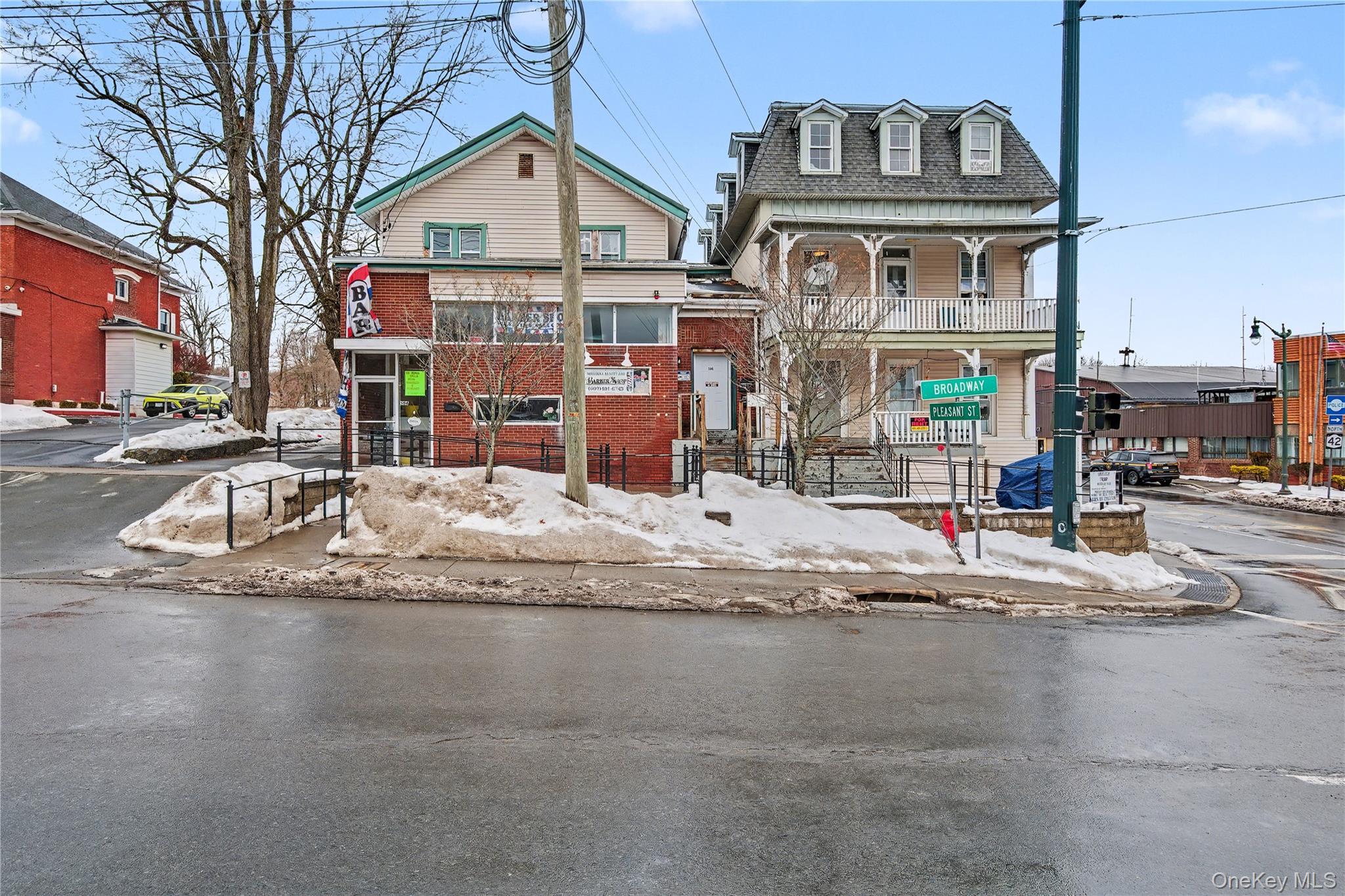 Victorian home with mansard roof, brick siding, roof with shingles, and a fenced front yard