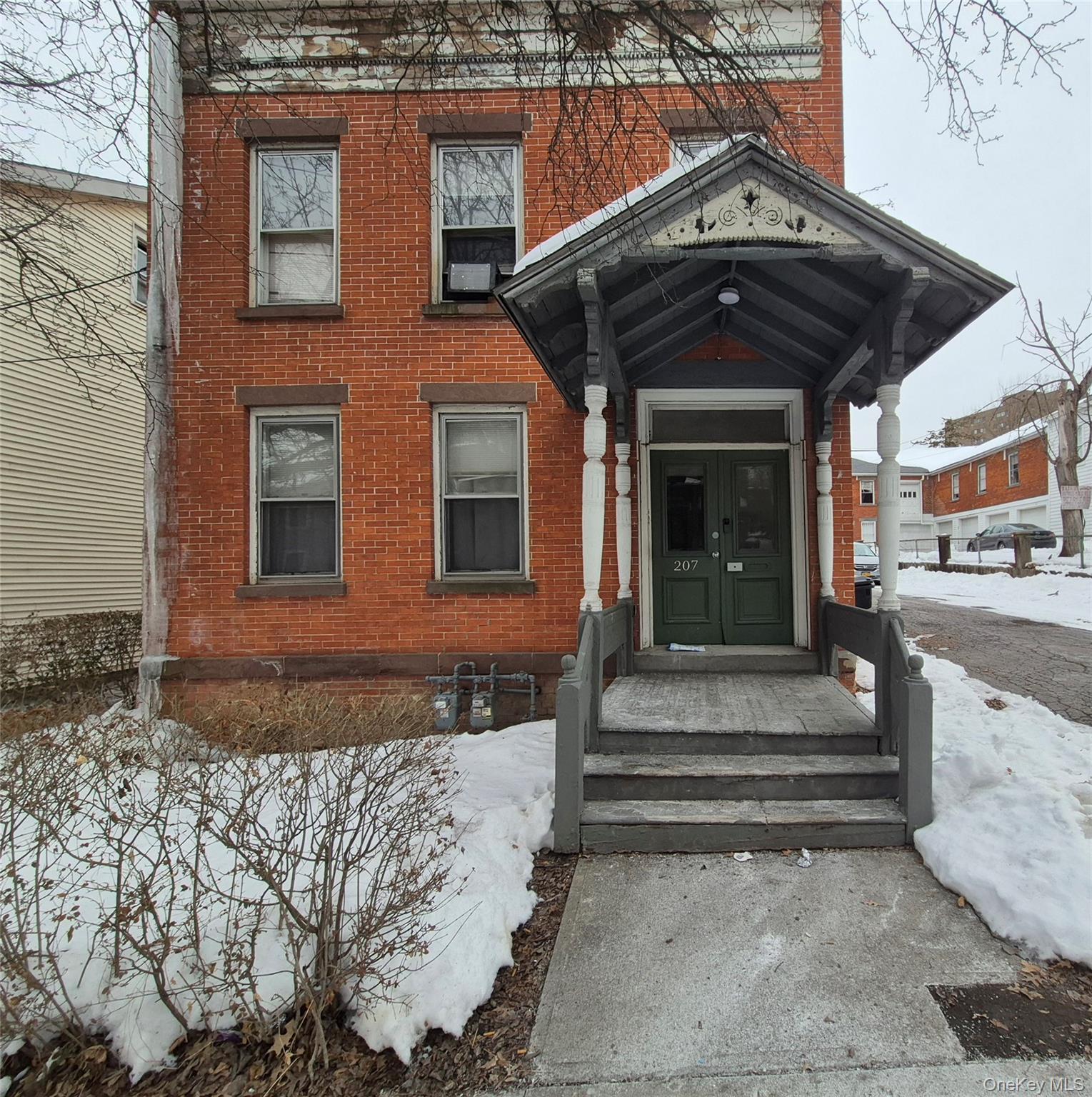 Snow covered property entrance with brick siding and french doors