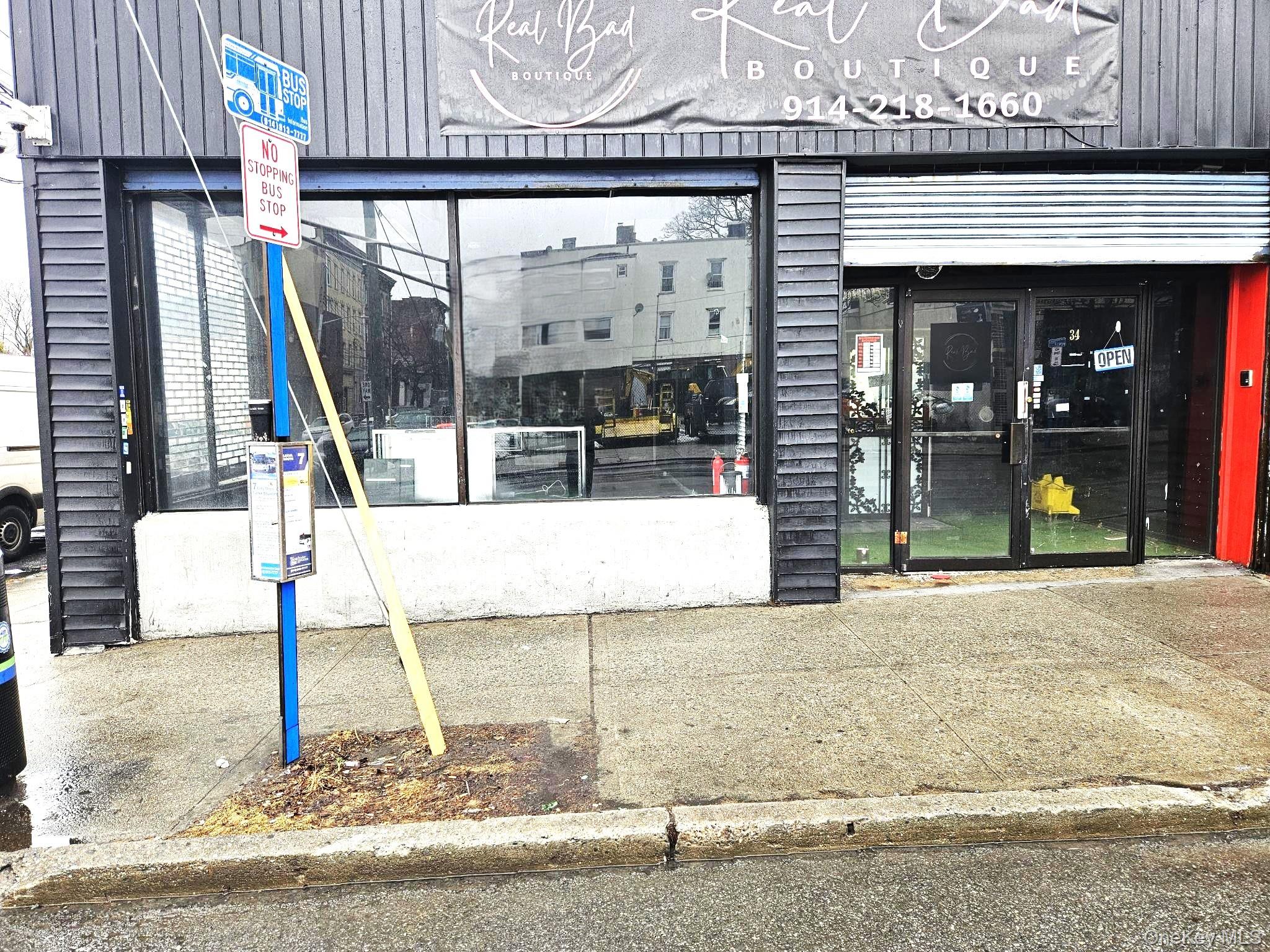 Front view of storefront. features a bus stop in front.