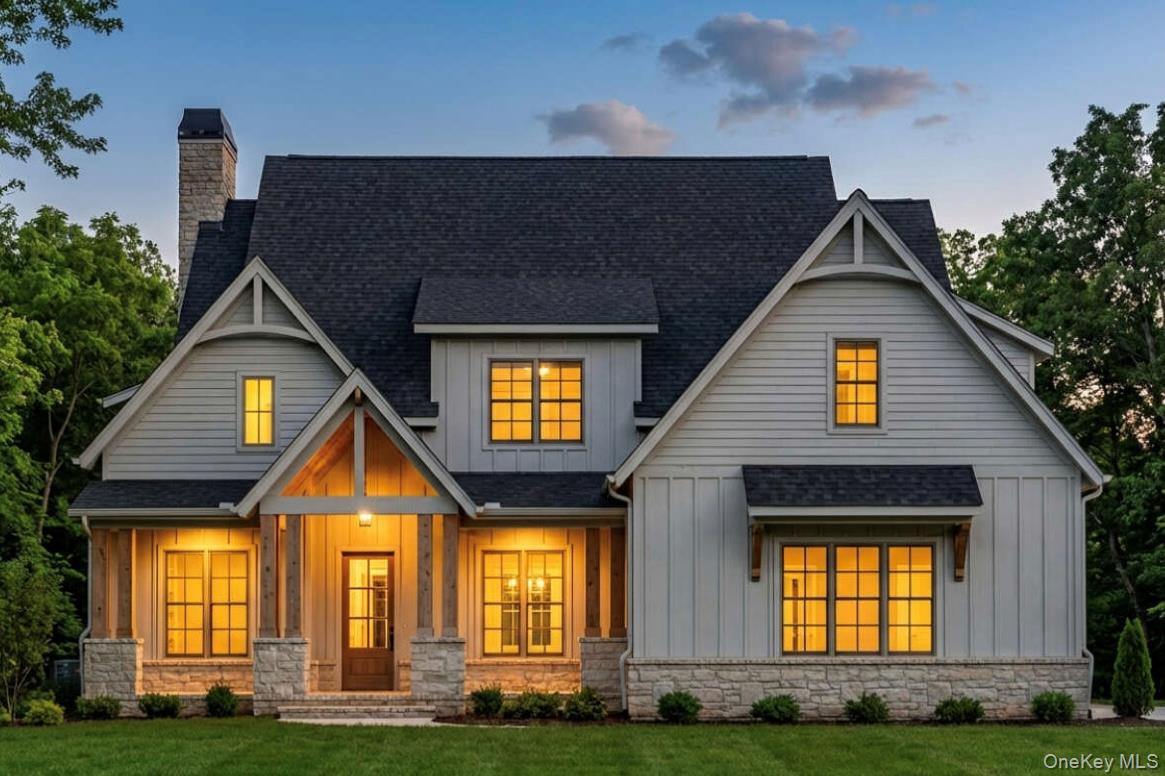 View of front of home featuring board and batten siding, covered porch, a chimney, and a yard