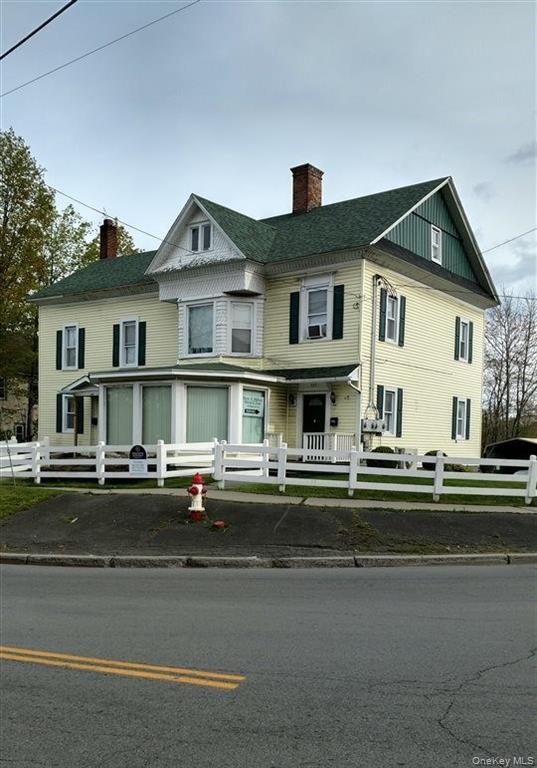 View of front of house with a fenced front yard, a chimney, and covered porch