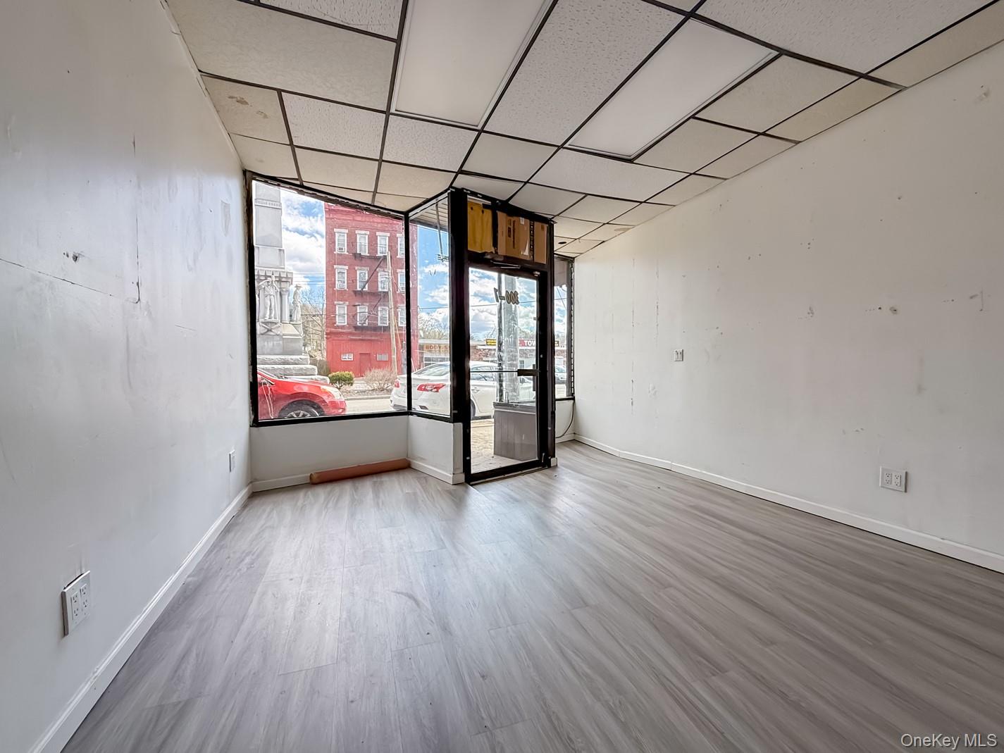 Empty commercial space featuring light wood-style flooring and a drop ceiling
