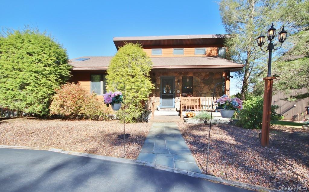 View of front of home featuring covered porch and stone siding