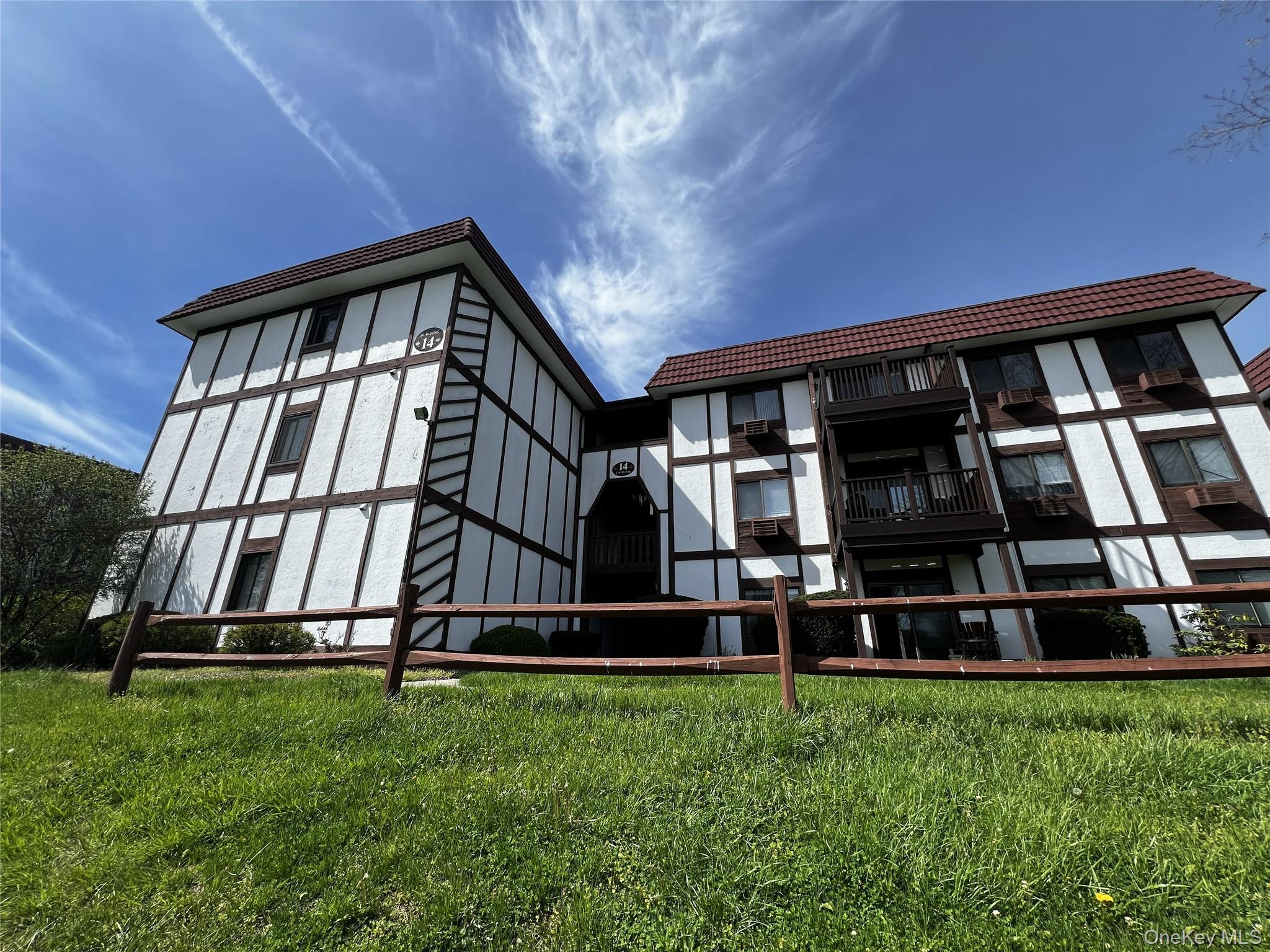 Multi-story residential condo featuring Tudor-style architectural elements with white stucco and dark timber detailing
