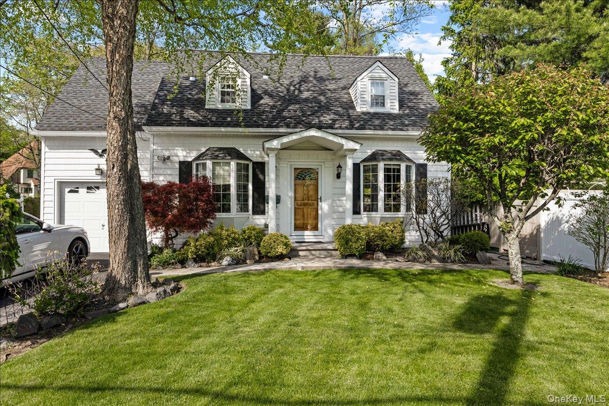 White siding residence featuring a dark shingle roof, dormer windows, and a bay window