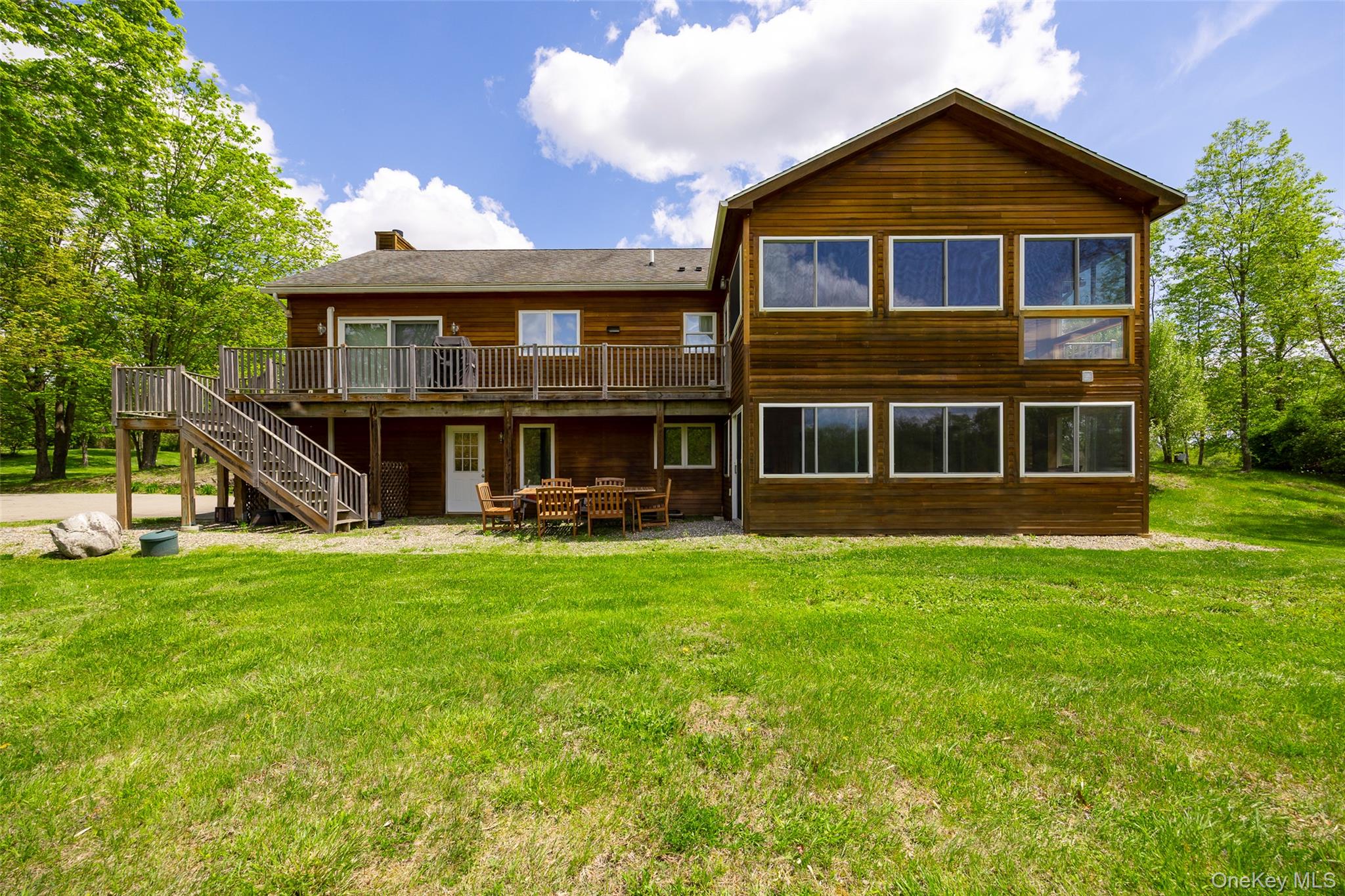 Rear view of property with a wooden deck, stairs, a yard, a chimney, and a patio area