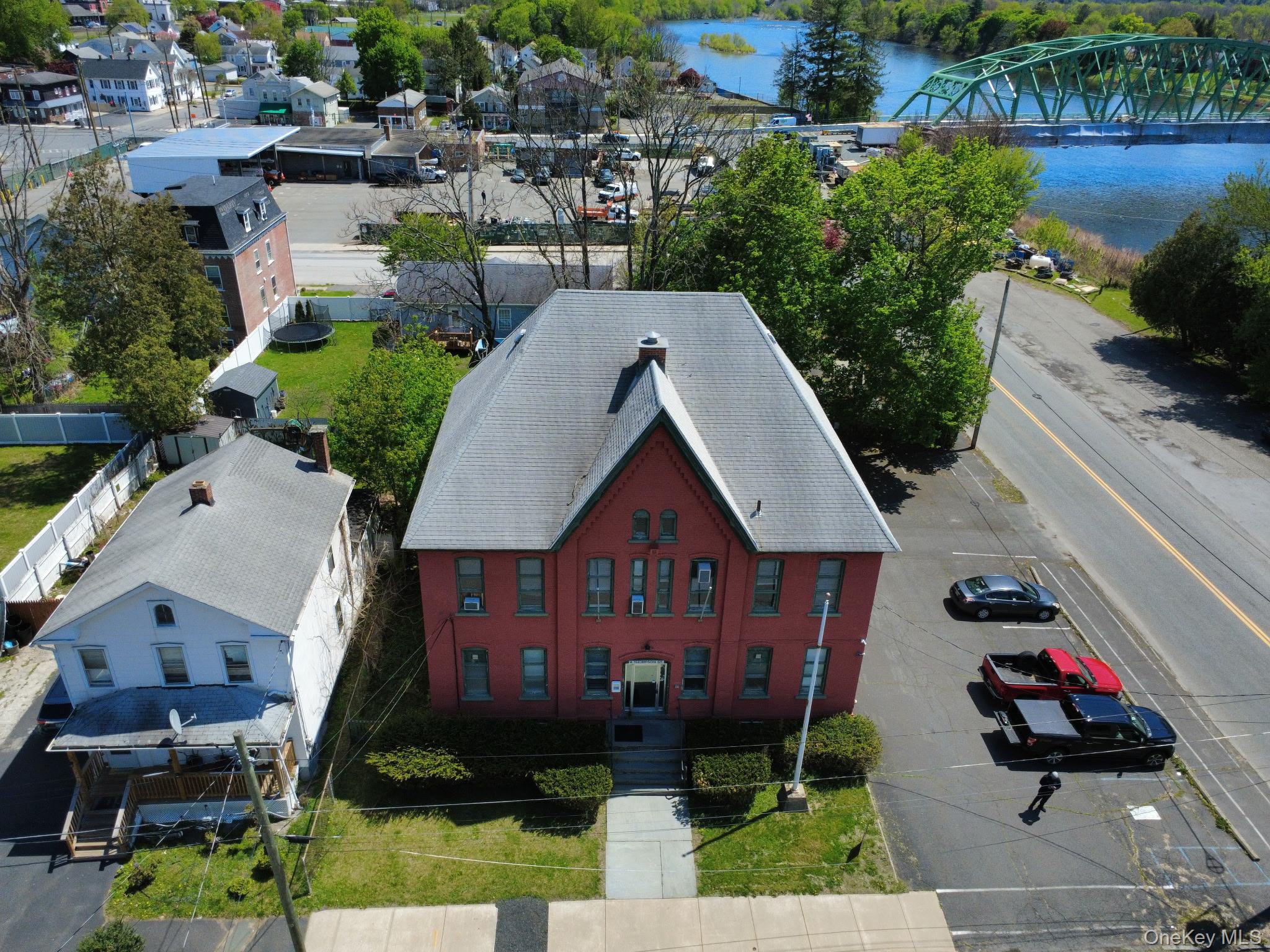 Brick building featuring a steeply pitched roof, multiple window openings, and a front entrance