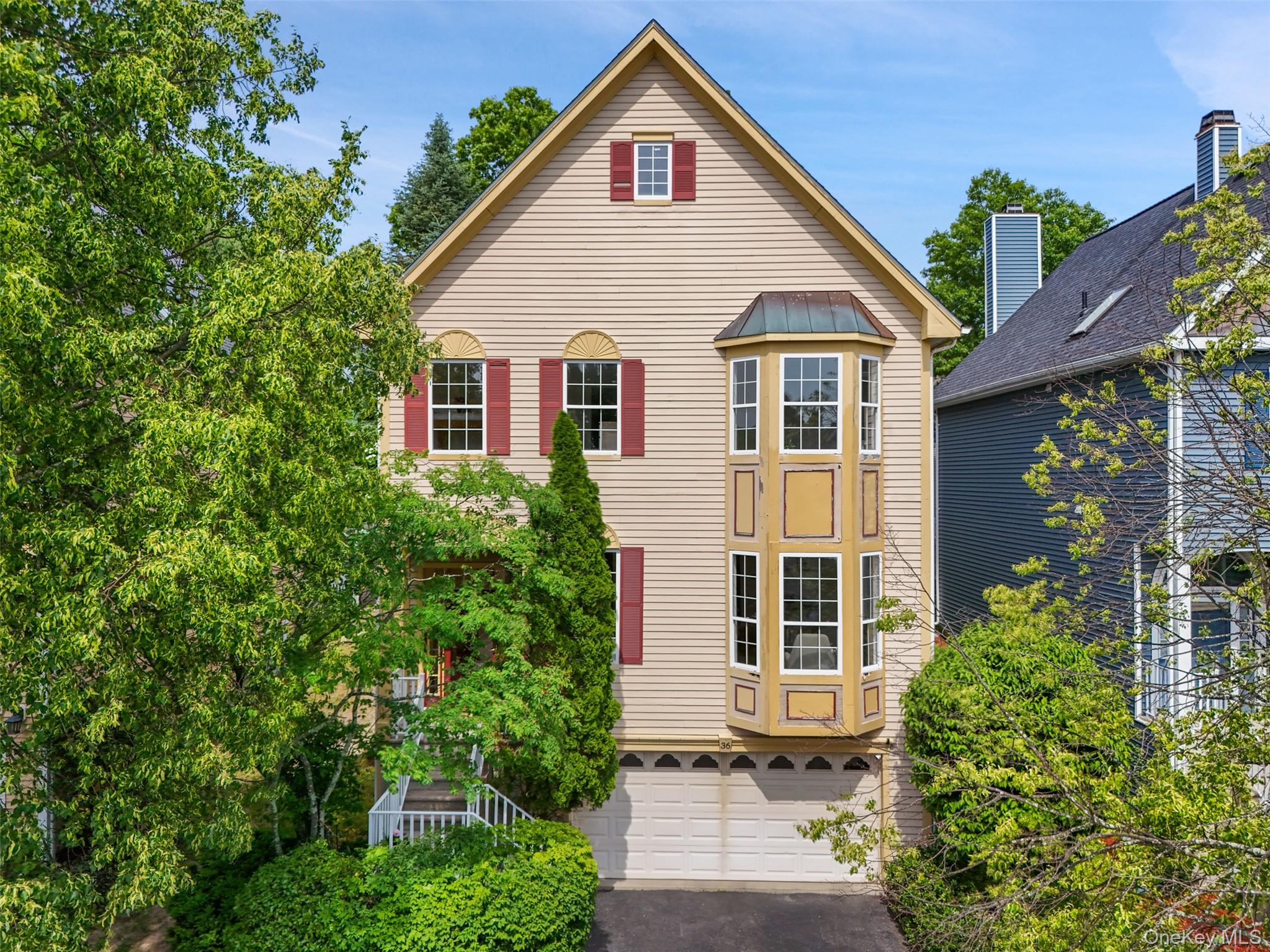Traditional Contemporary-style exterior featuring light-colored siding, a prominent bay window, and red window shutters