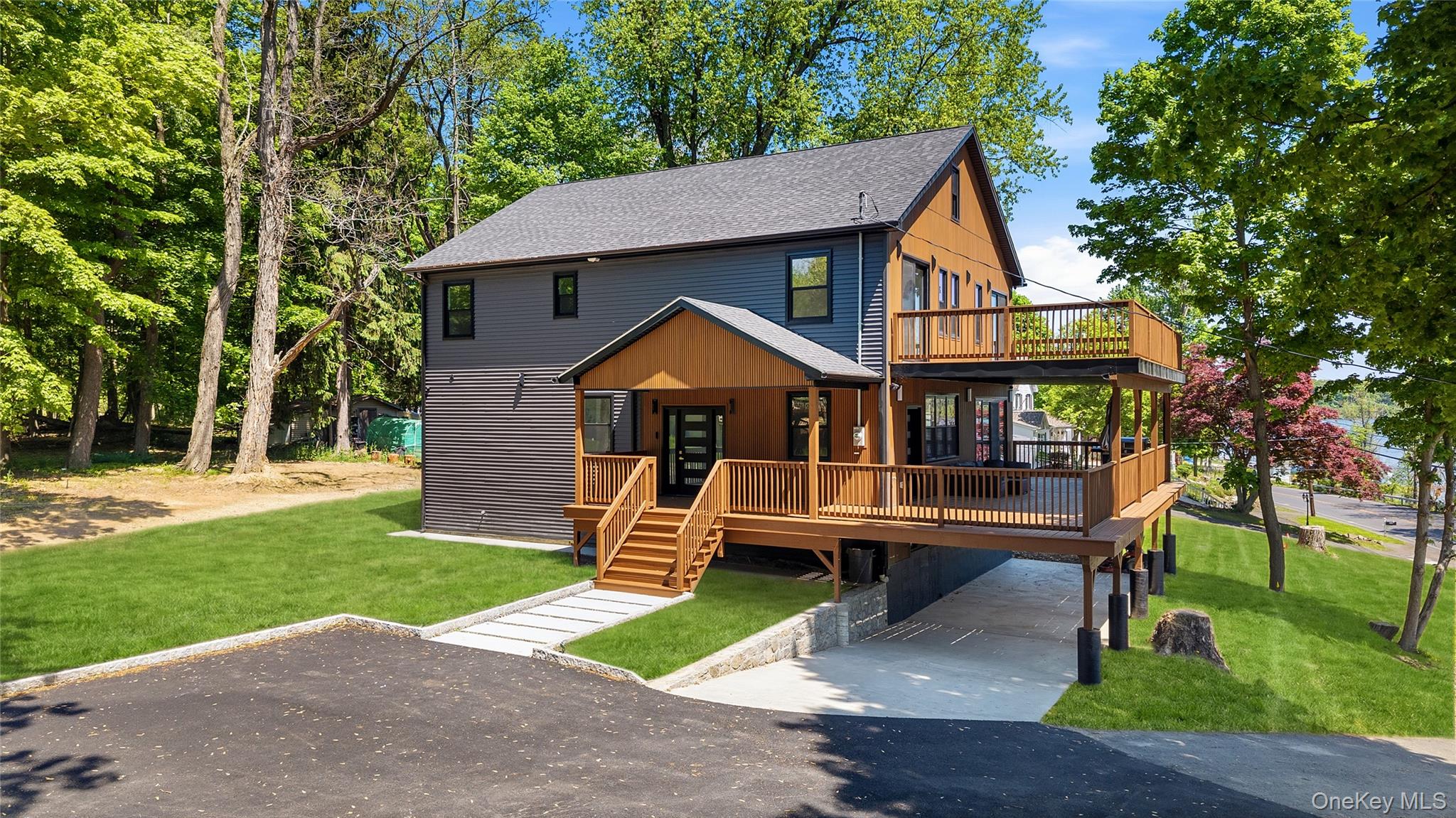 Modern multi-level residence featuring dark siding, natural wood accents, and a tiered deck system