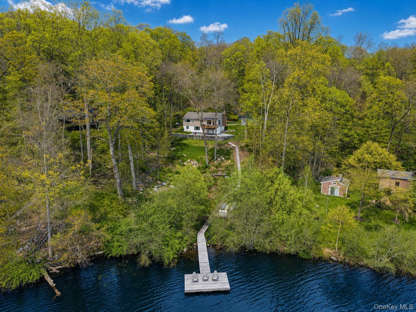 Waterside property featuring a private dock, a two-story residence with a balcony, an expansive wooded lot.