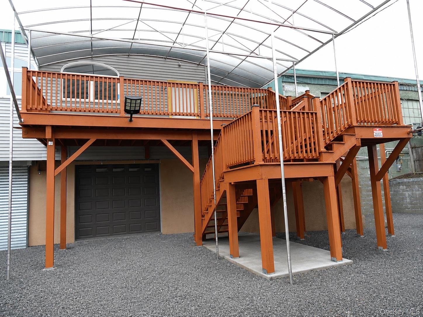 Elevated wood-tone deck with full staircase access and protective railings-Entrance to office space