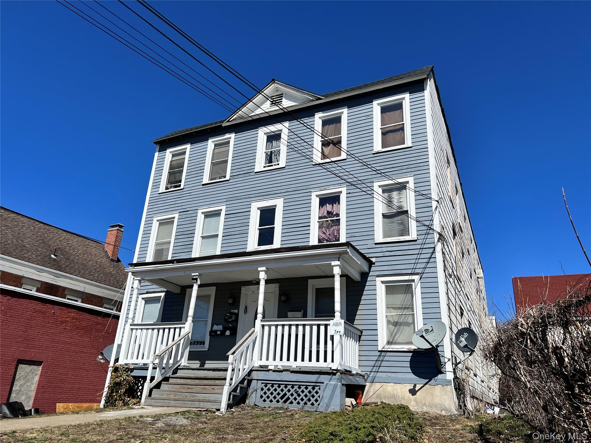 Three-story residential structure featuring light blue horizontal siding and multiple windows with white trim