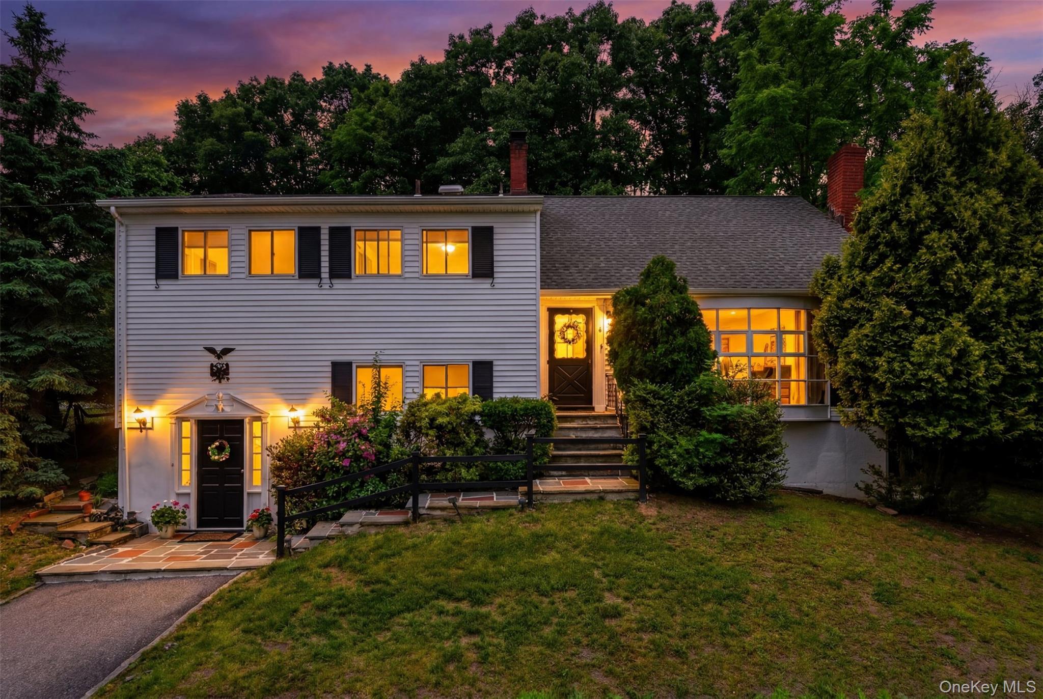 Colonial-style residence featuring white siding, black shutters, and a prominent front entry with a portico