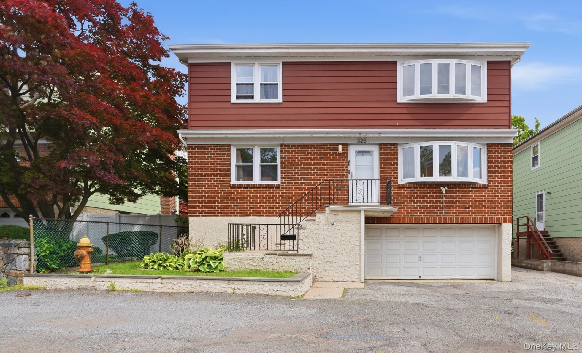 Two-story residence featuring a brick first level and red siding on the second level