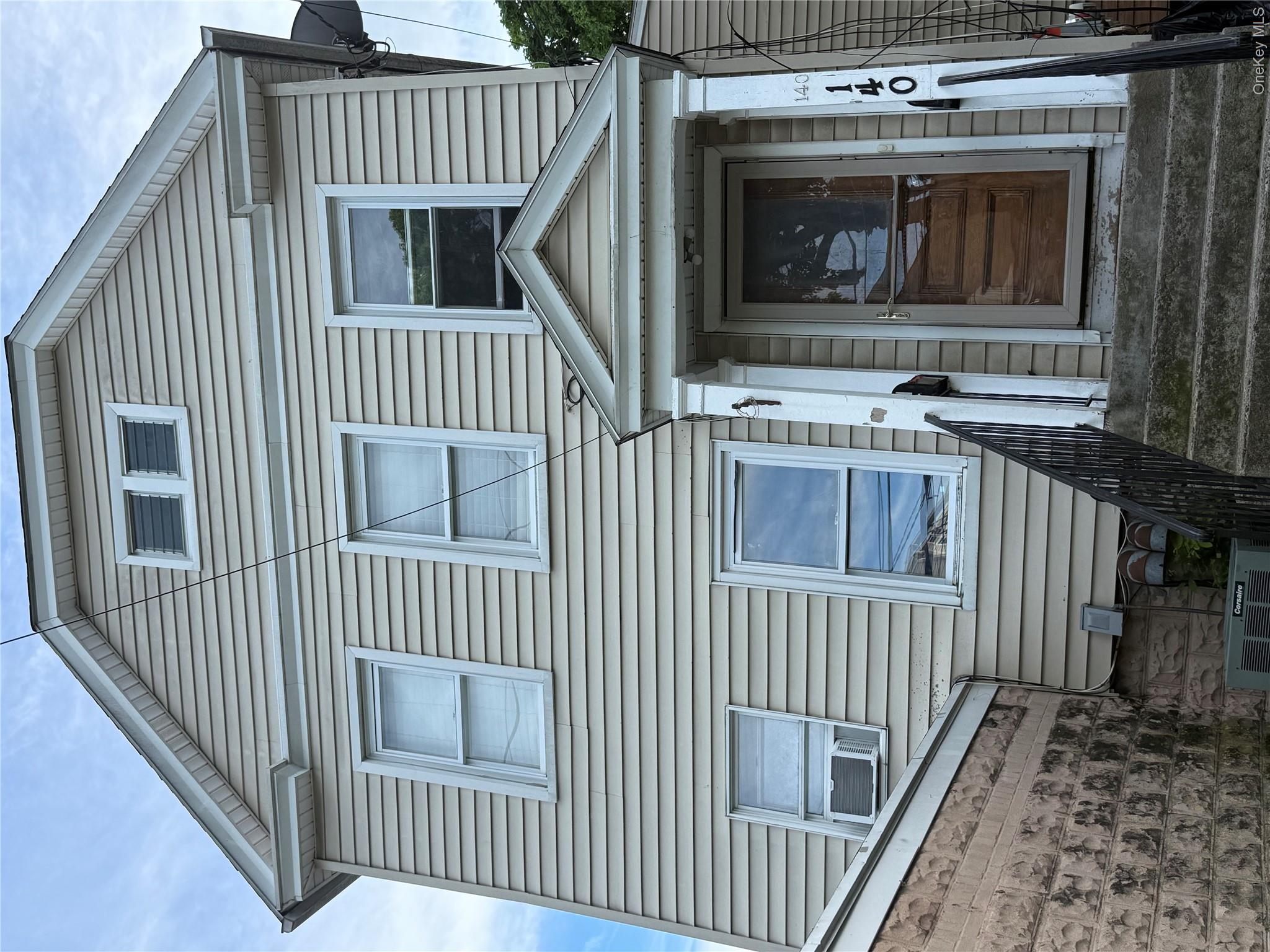 Three-story exterior featuring tan siding and multiple windows