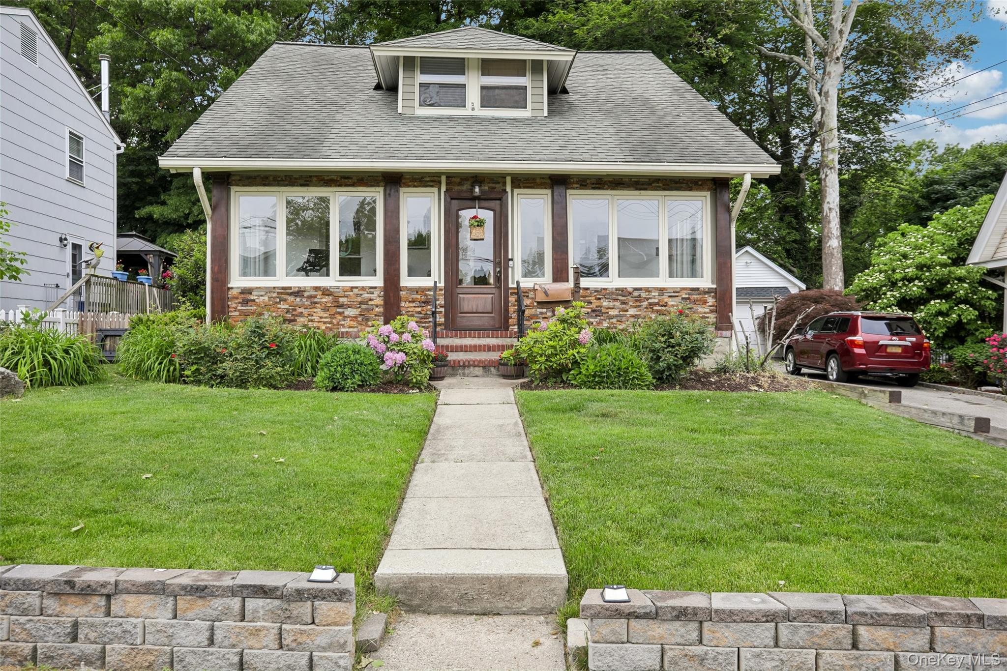 Craftsman-style home, dormer window, and mature landscaping