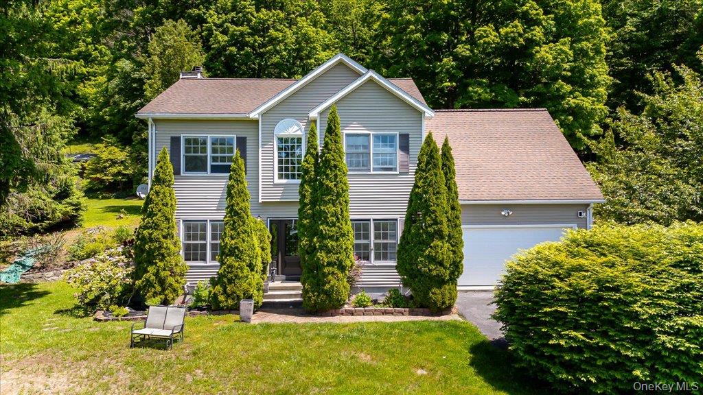 Two-story residence featuring light gray siding with dark shutters, an arched decorative window, and a two-car garage