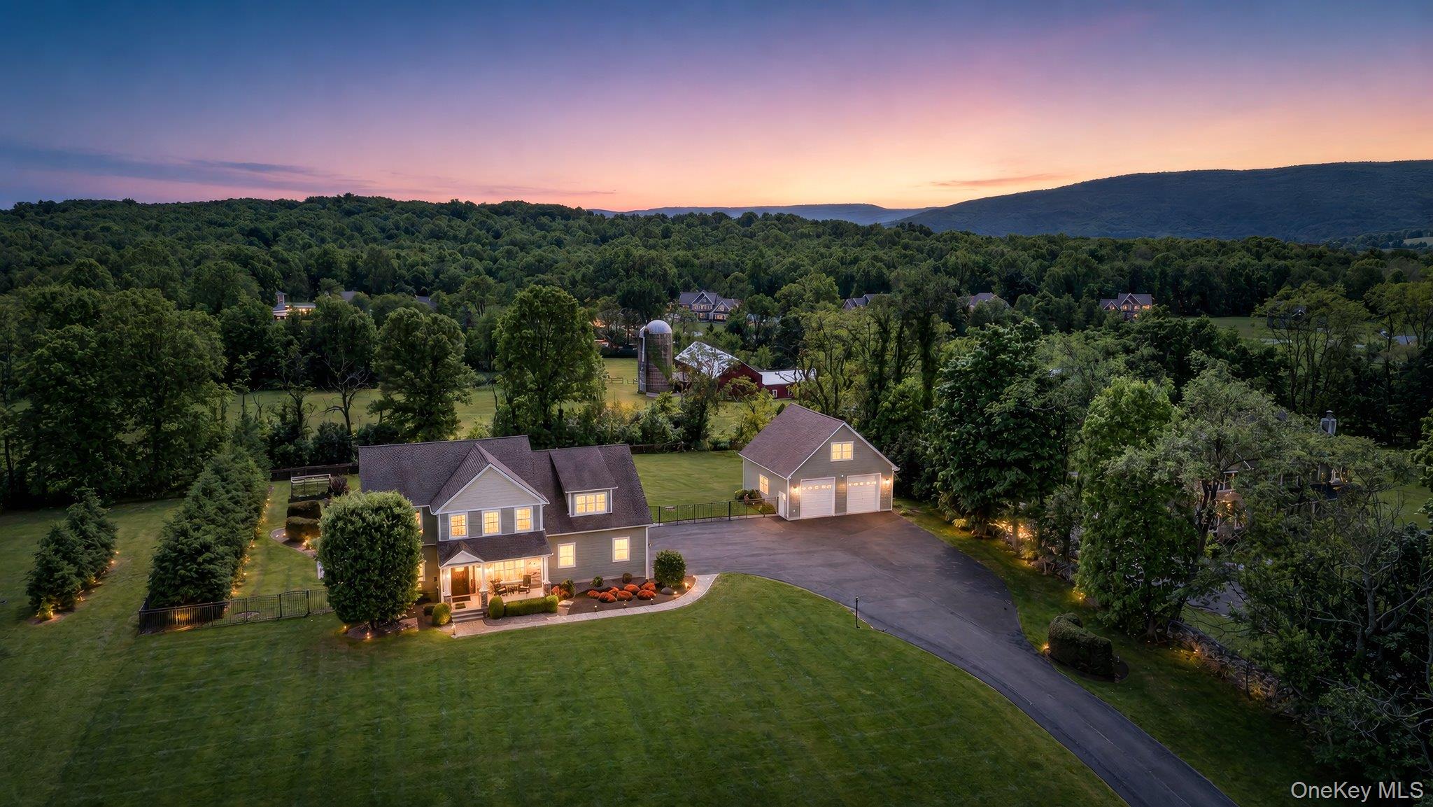Spacious property featuring a two-story residence with a detached three-car garage, extensive paved driveway, and mature landscaping