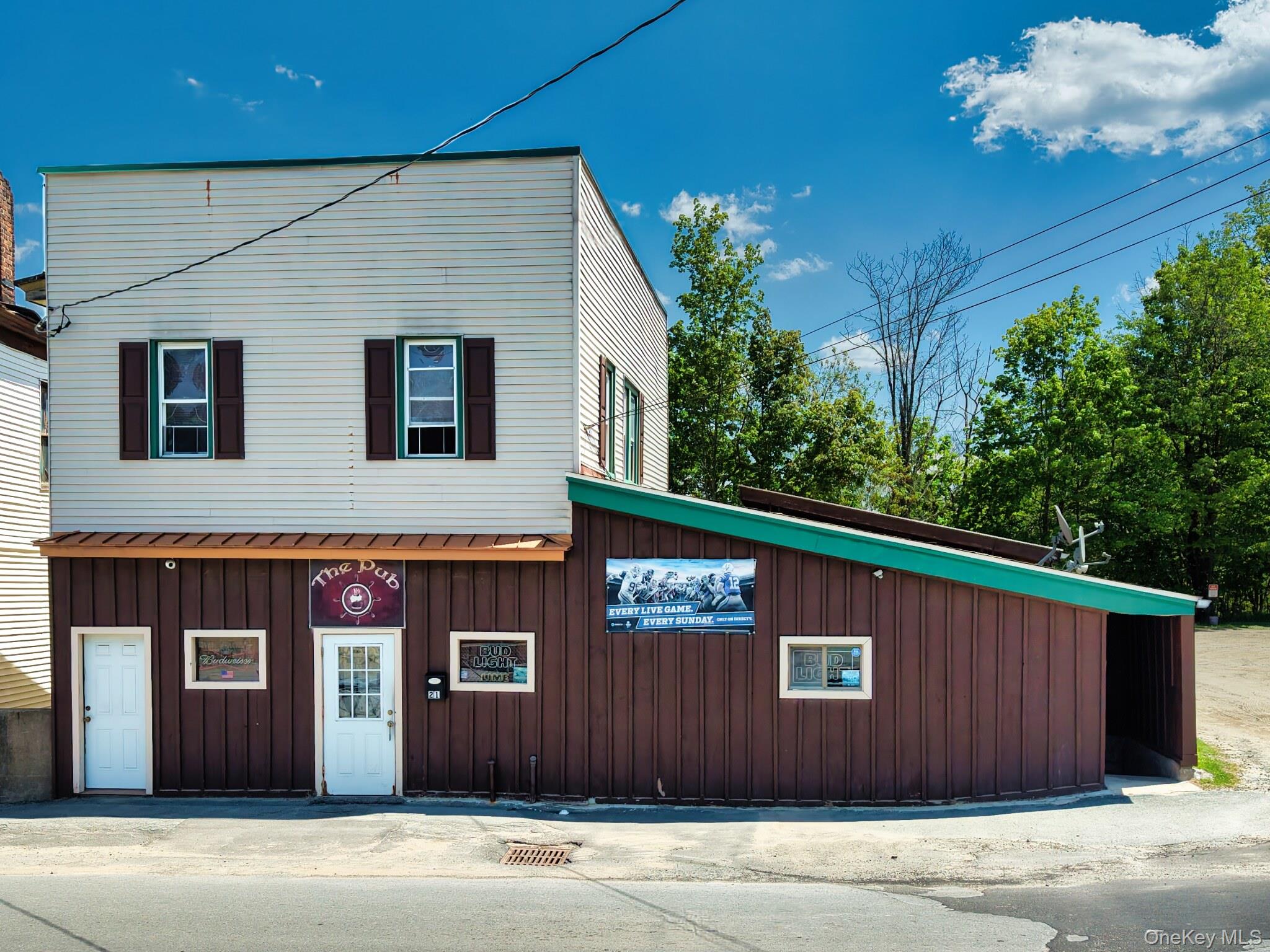 Two-story commercial building featuring a cream-colored upper facade with brown shutters