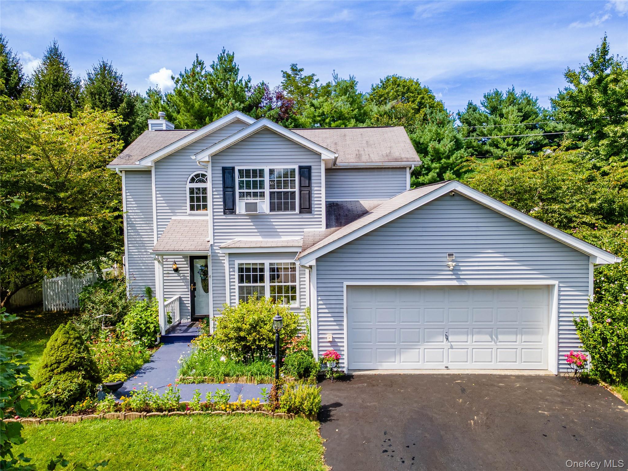 Traditional home with driveway, roof with shingles, a chimney, and an attached garage