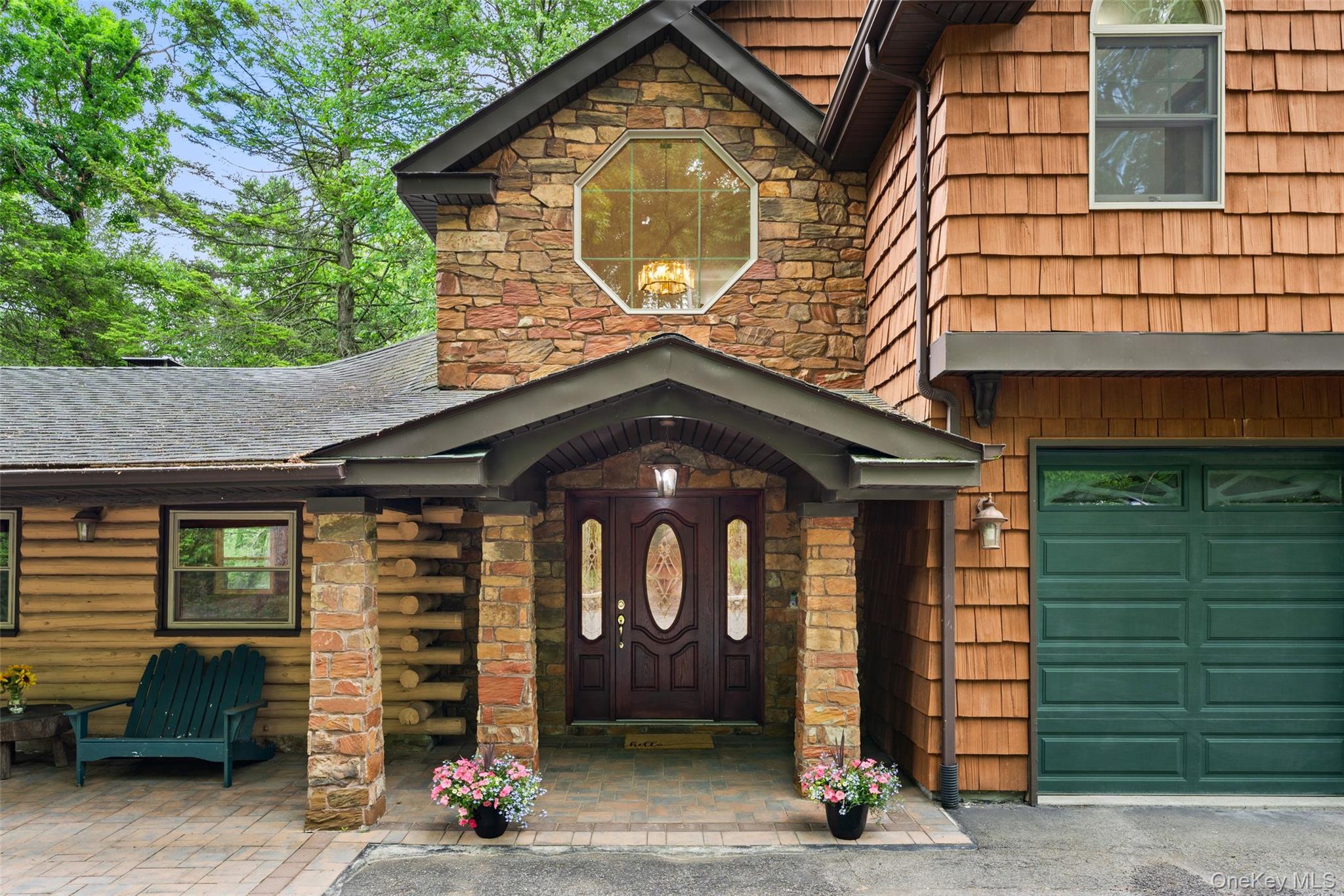 Stone and cedar shake exterior featuring a covered entry, arched dark wood front door with decorative glass, and an octagonal window