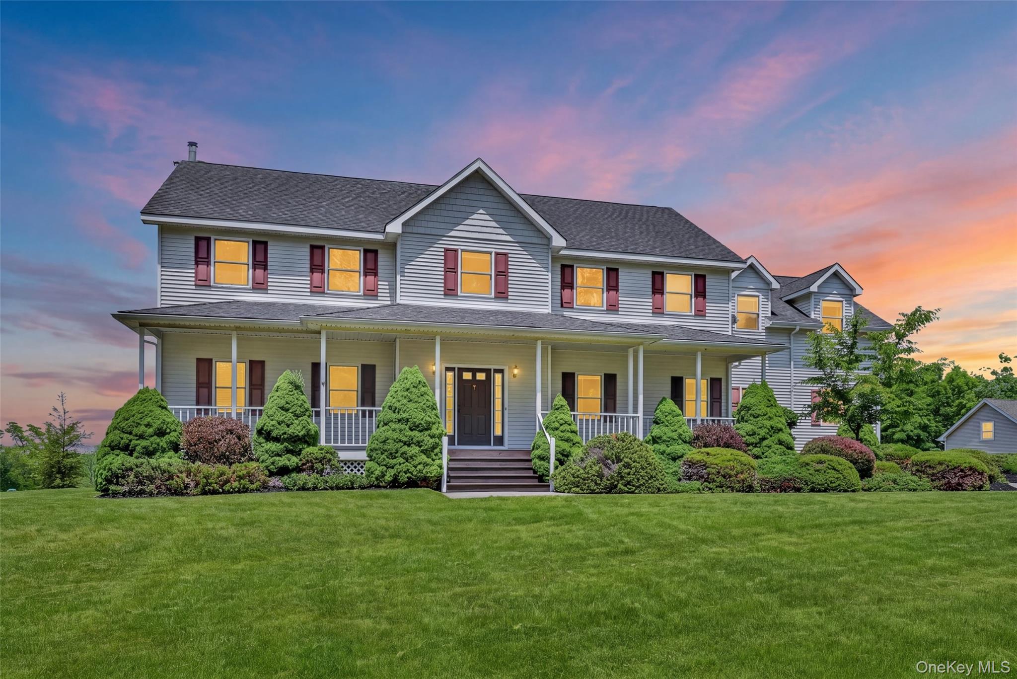 Two-story residence featuring light gray siding, dark roof shingles, and red window shutters