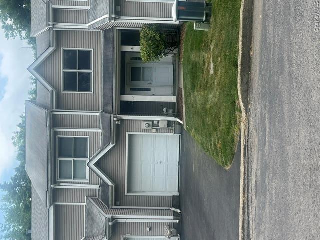 Two-story townhome featuring neutral-toned siding, an attached garage, and a paved driveway