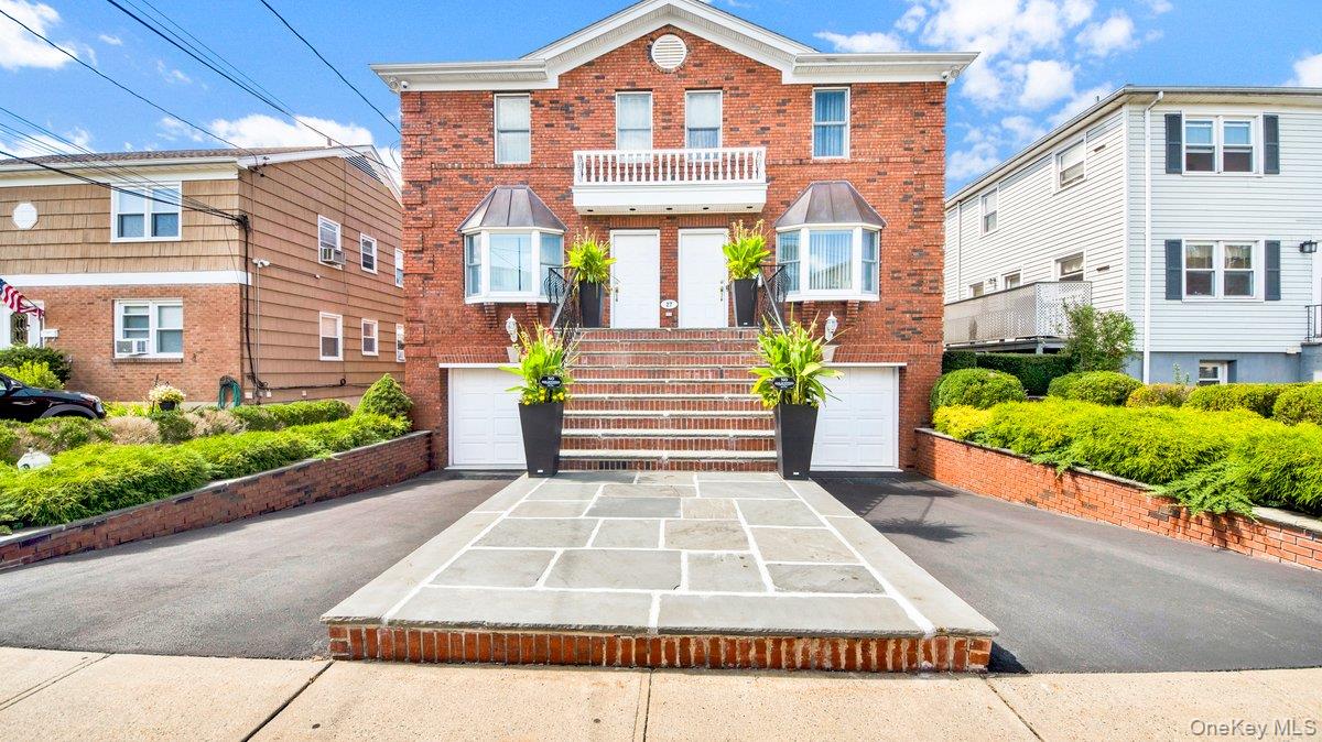 Brick Multi Family home featuring a symmetrical design, dual entry doors, and a stone-paved walkway