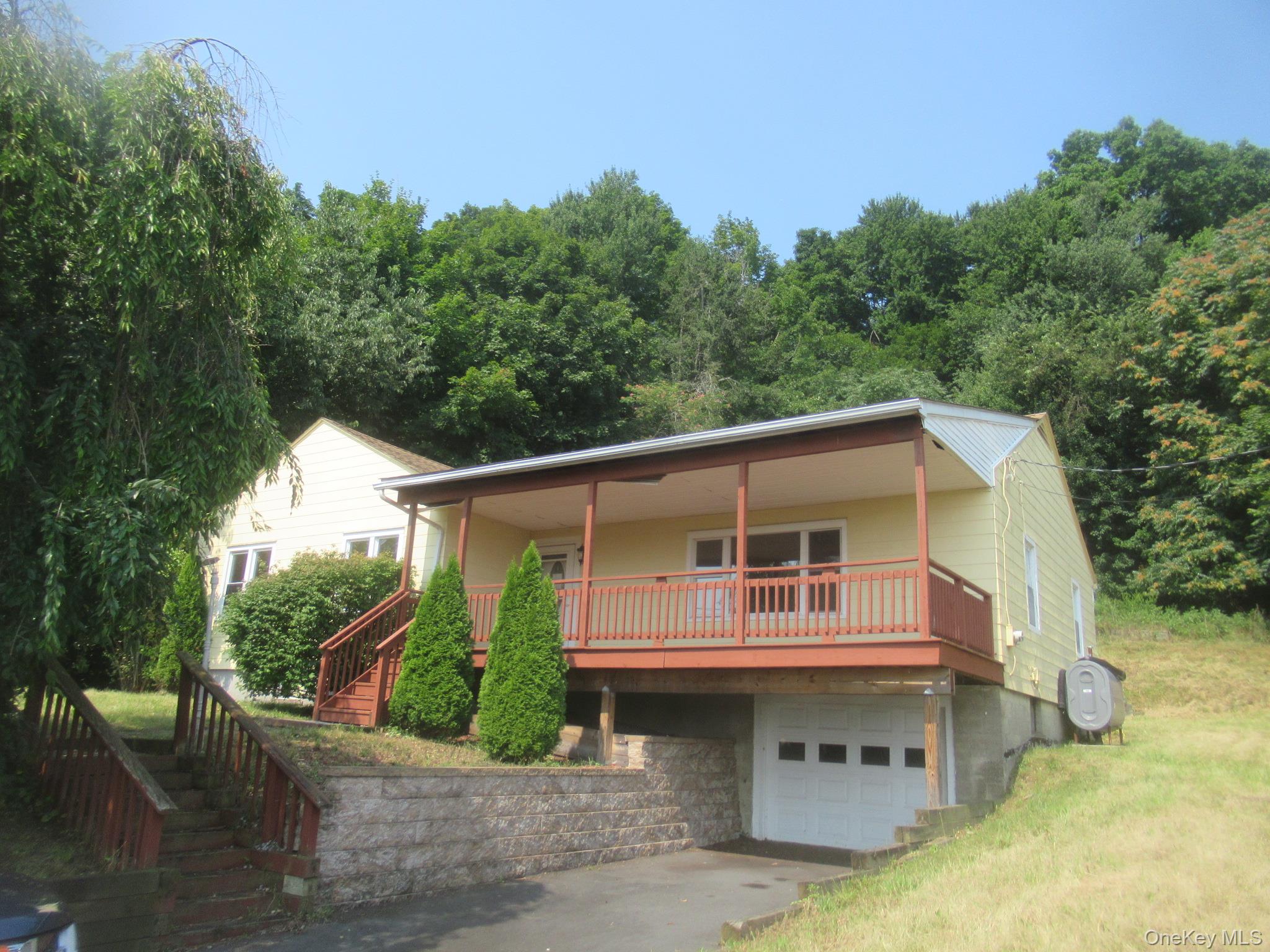 View of front of home featuring a porch, stairway, driveway, an attached garage, and heating fuel