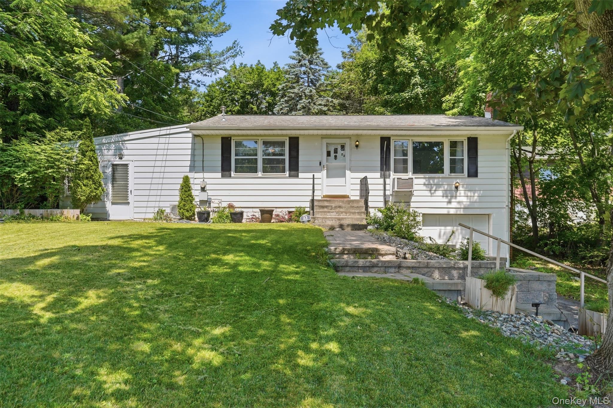 Split-level residence featuring white siding, dark shutters, and a prominent front entrance with stone steps