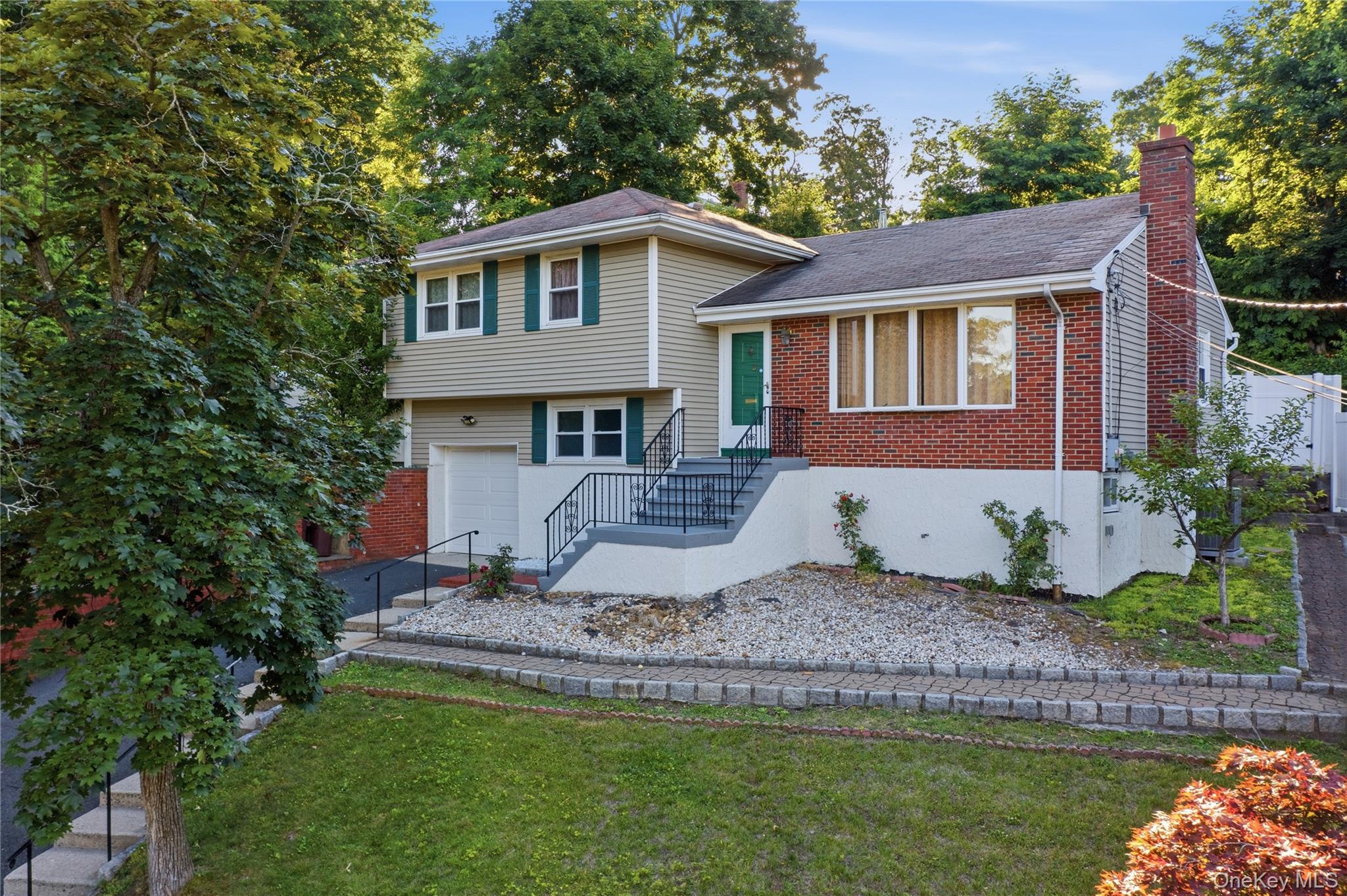 Split-level residence featuring a brick facade, beige siding, and a prominent brick chimney
