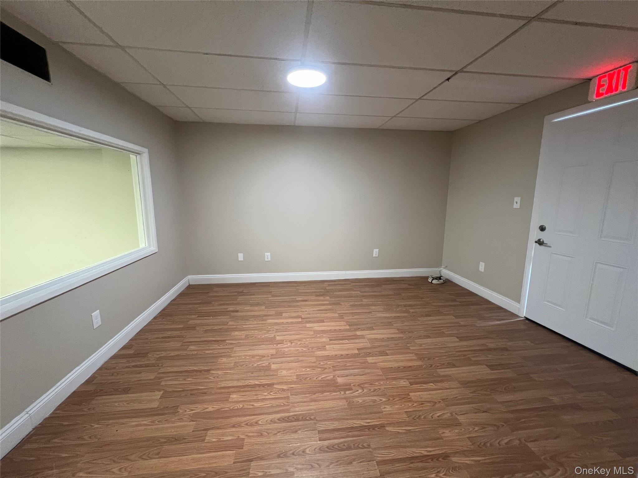 Finished basement featuring wood finished floors, baseboards, and a paneled ceiling
