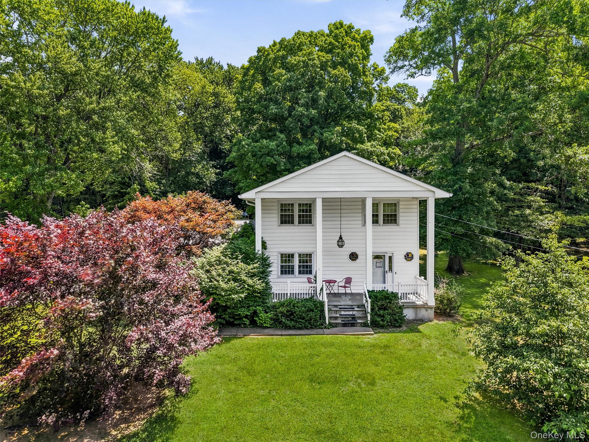 Two-story residence featuring a classic white facade, columned porch, and multiple windows