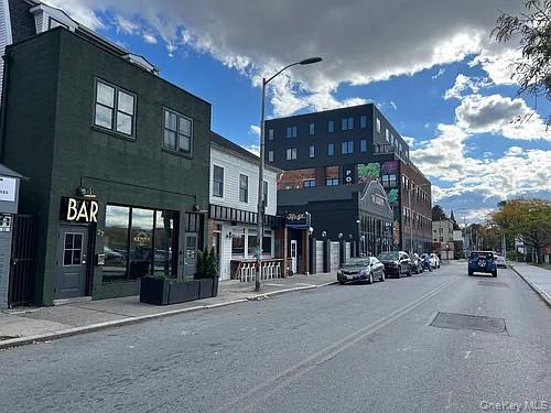 Street-level commercial property featuring a dark green facade with a prominent \"BAR\" sign, large display windows, and a dedicated entrance