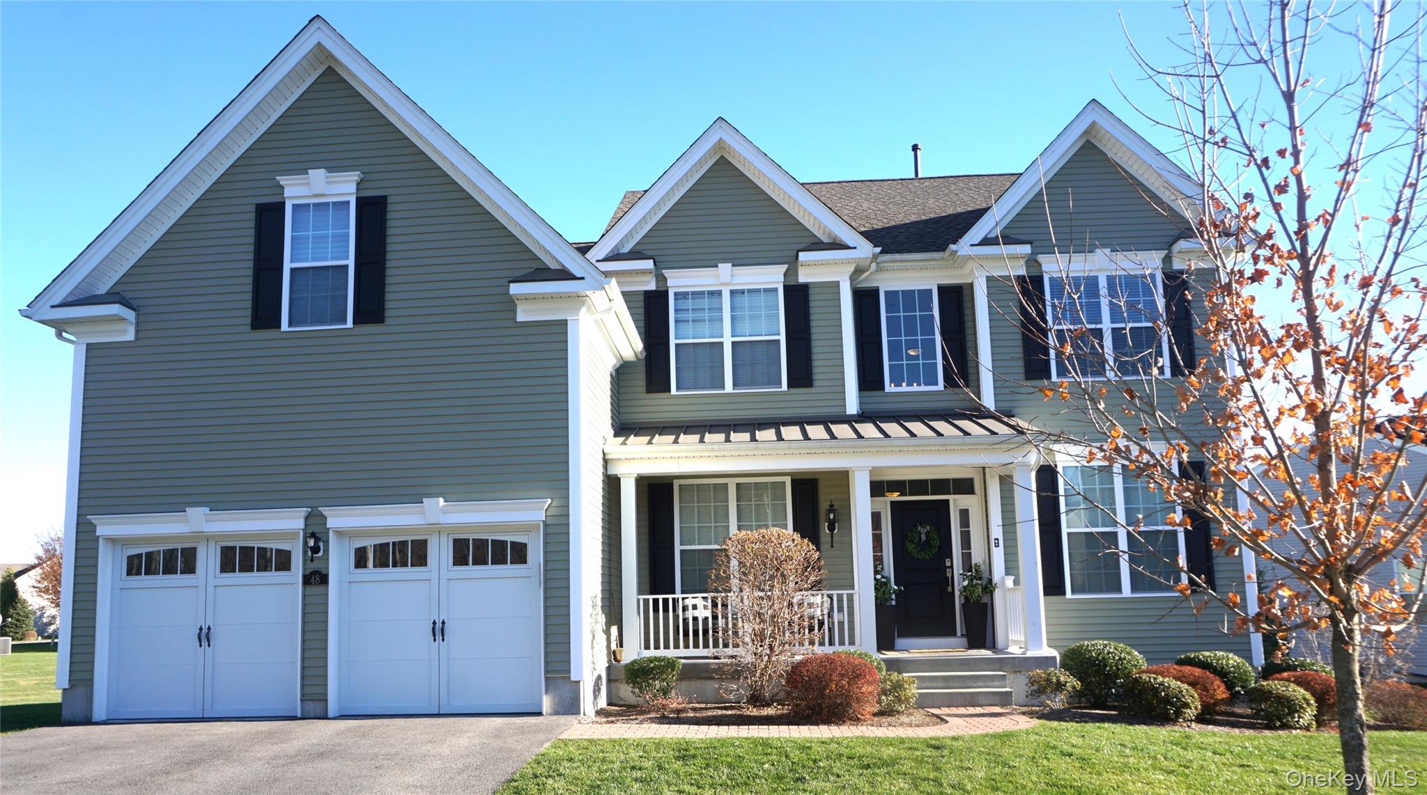 Traditional-style home featuring a porch, an attached 2 car garage, driveway, and a front yard