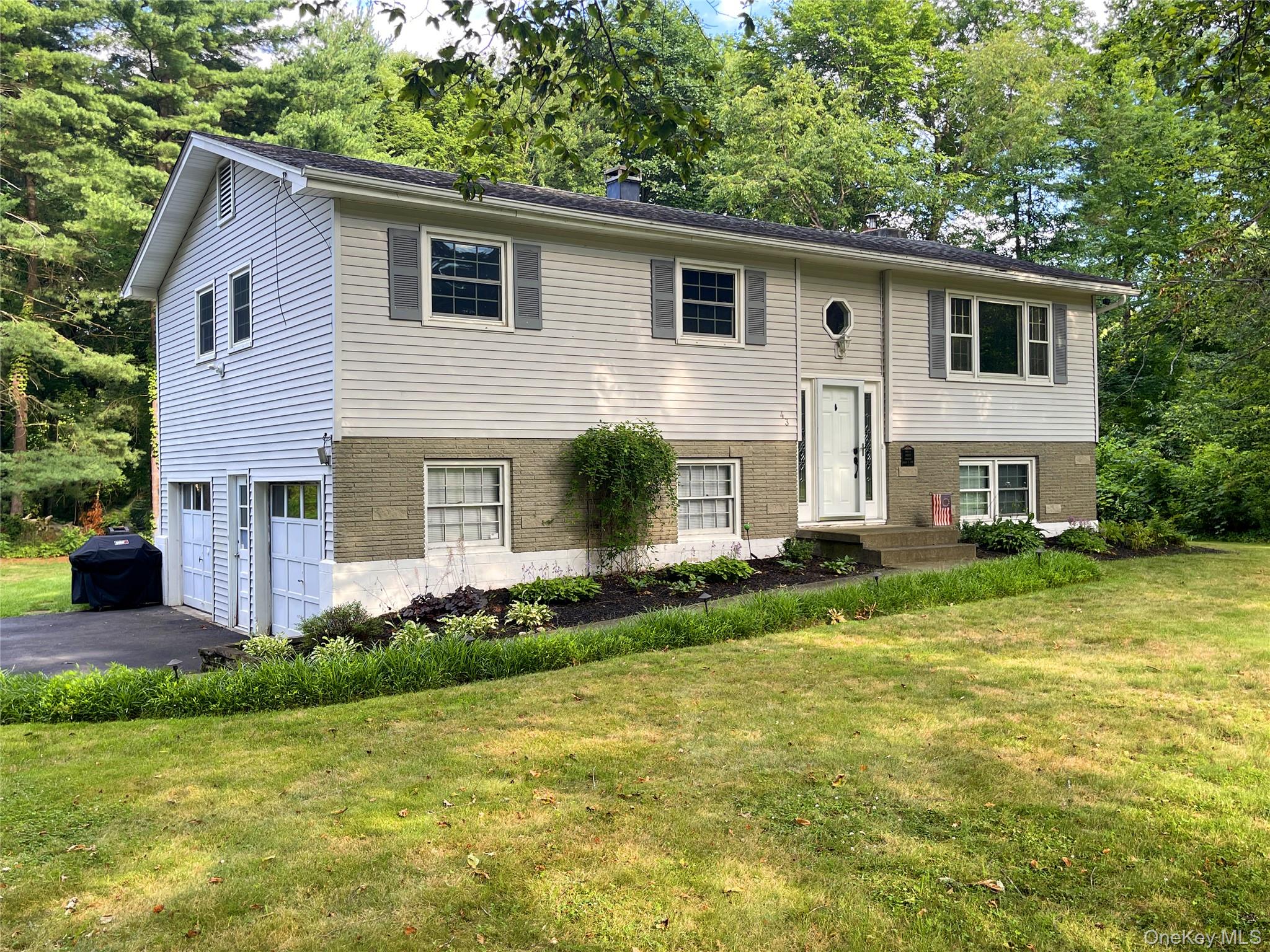 Raised ranch featuring vinyl siding, a brick facade, and an attached two-car garage