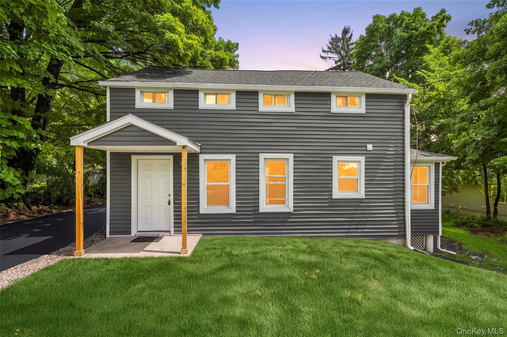 Exterior featuring dark grey horizontal siding, white trim windows, and a covered front entry with natural wood posts