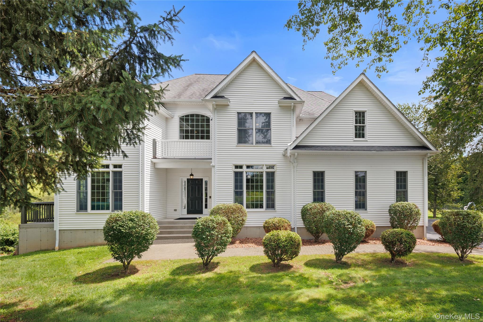 Impressive Colonial-style residence showcasing timeless elegance, exceptional architectural detail, and a grand sense of scale. The classic white exterior, striking multi-gable roofline, and expansive driveway create a commanding first impression, while t